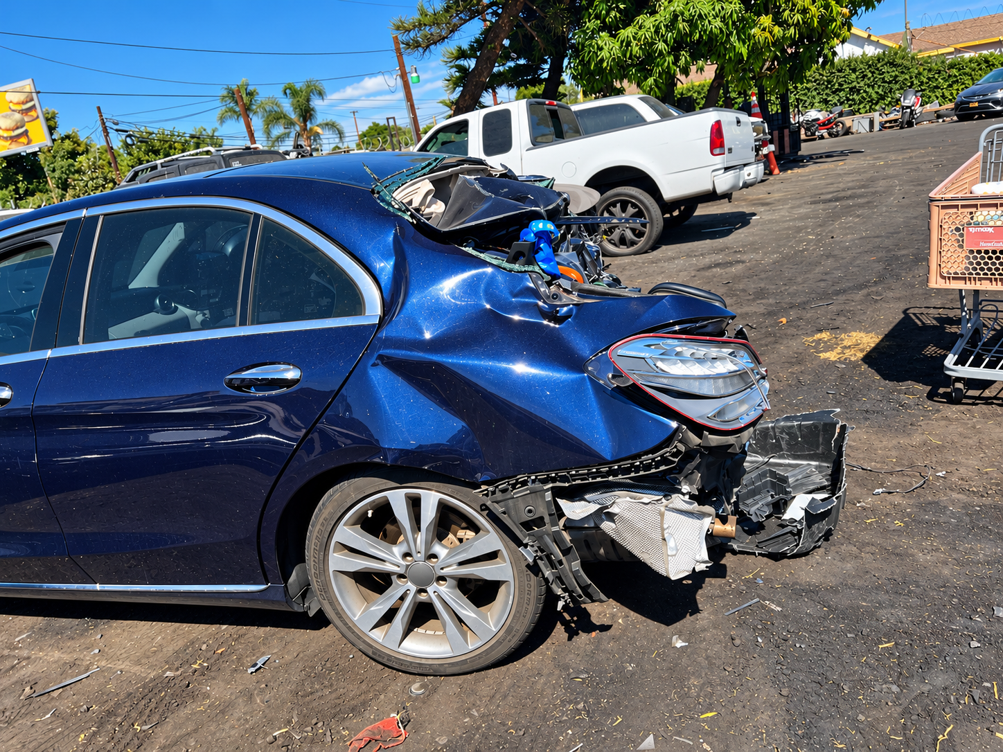crumpled blue sedan in daylight lot